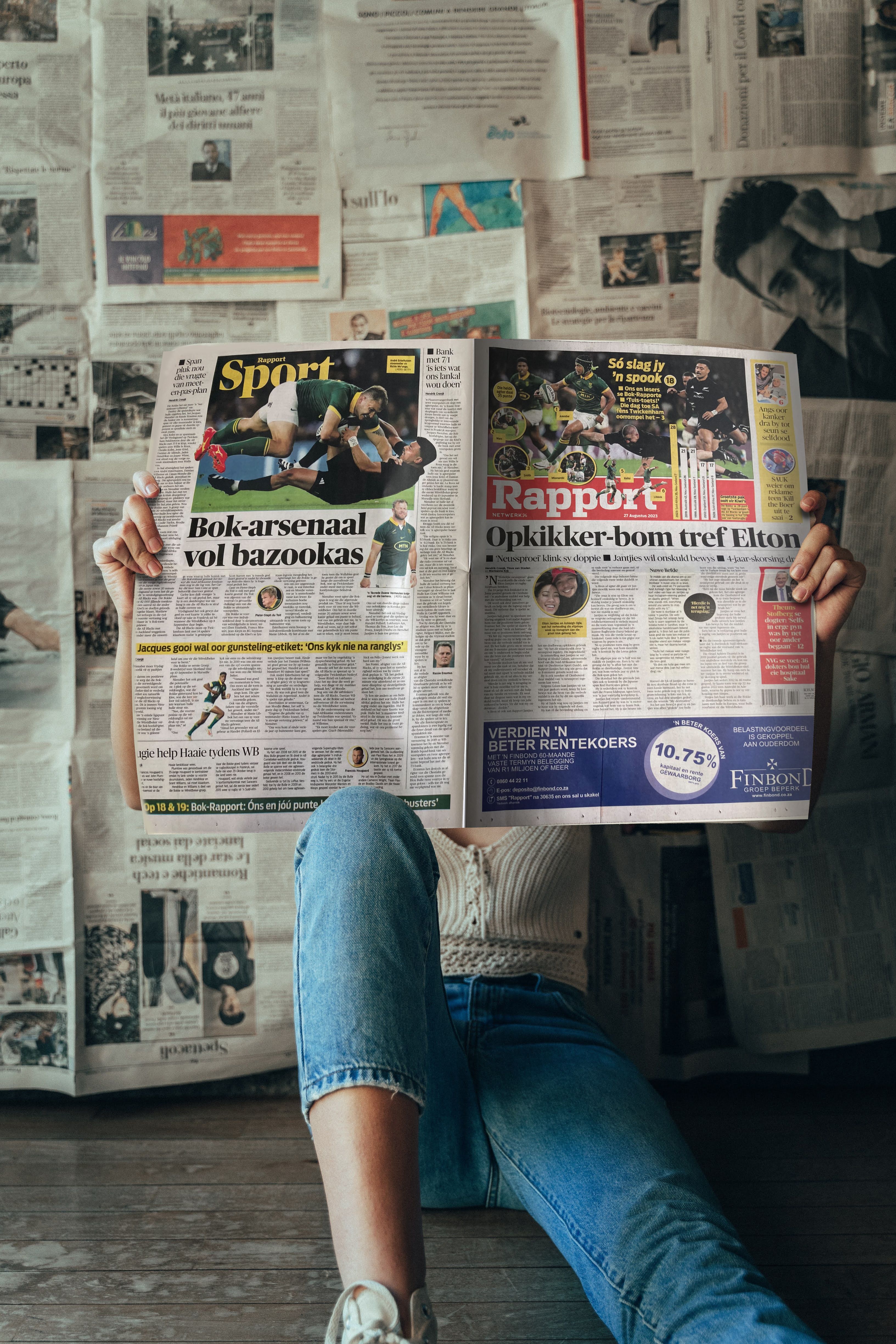 person in blue denim jeans holding white magazine